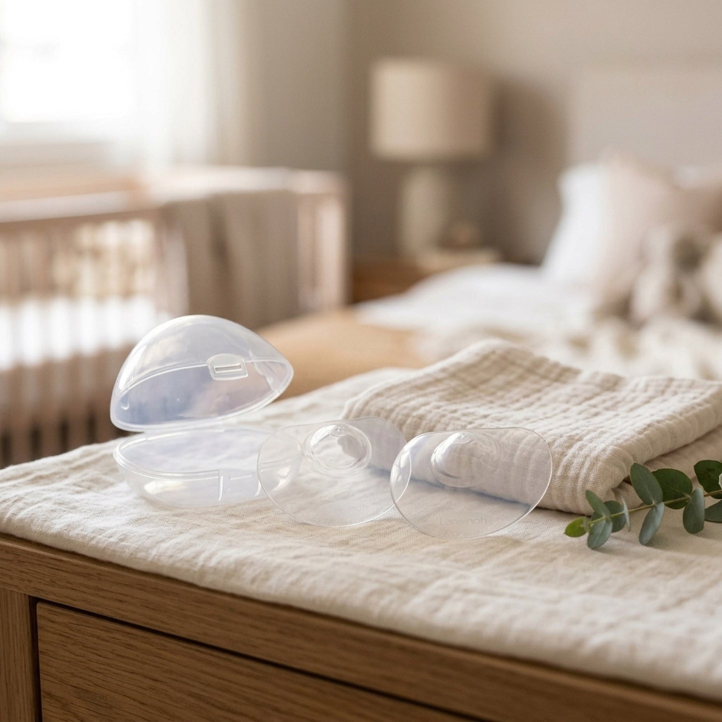 Pezoneras de contacto Lansinoh y su estuche sobre textil suave en ambiente de dormitorio