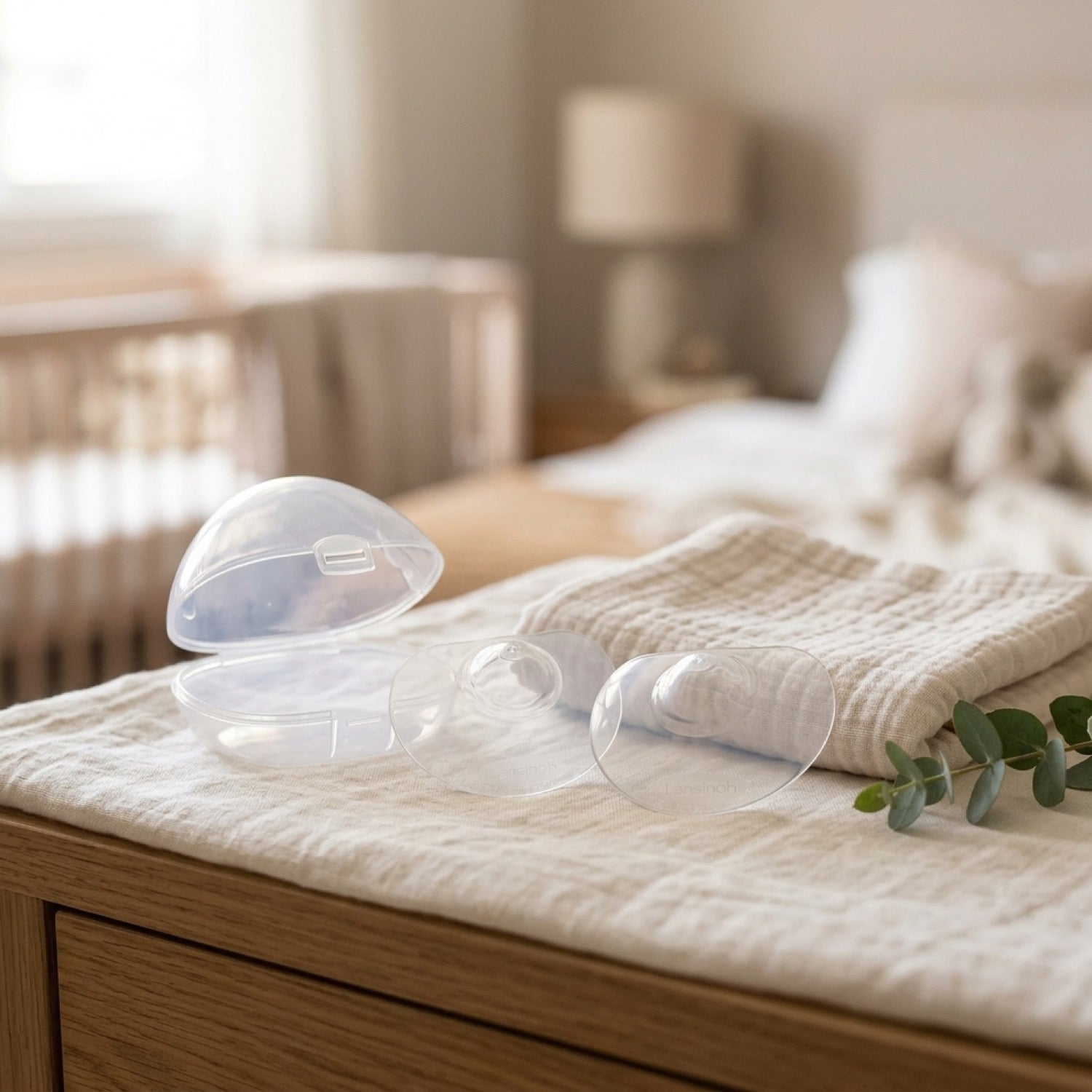 Pezoneras de contacto Lansinoh y su estuche sobre textil suave en ambiente de dormitorio
